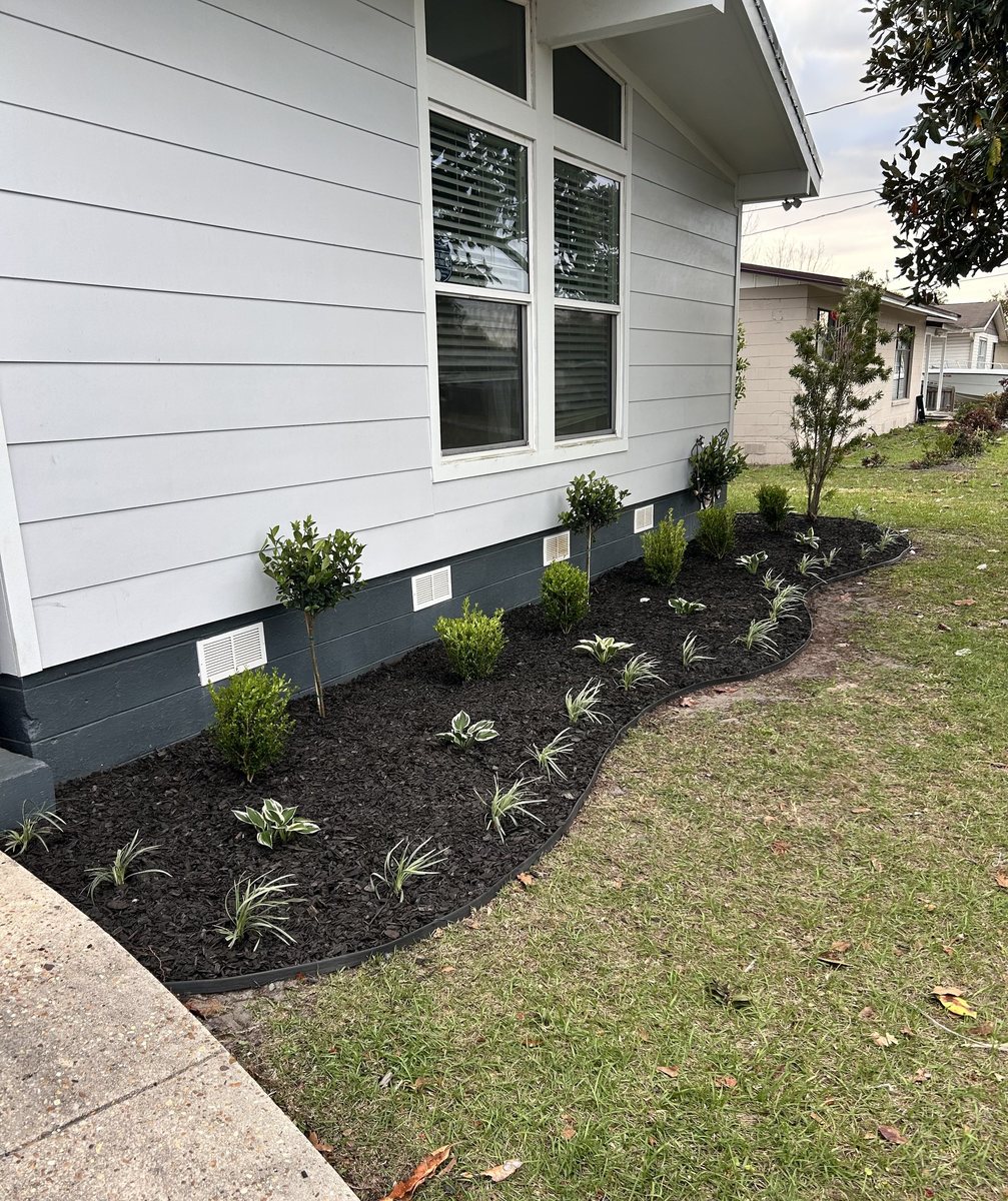 Side foundation mulch bed installation with curving border and structured plantings, Lynn Haven, FL